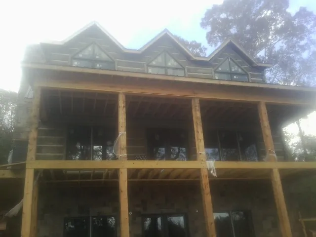 Dormers and porch framing on a large log home under construction — Roof Coating work by our crew in Eagle River
