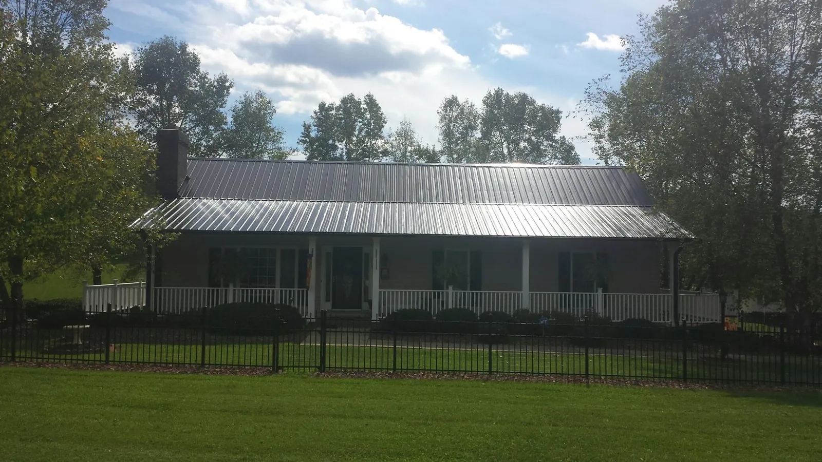 Gray metal roof on a brick ranch with a full width front porch — Gutter Guard Installation work by our crew in Eagle River