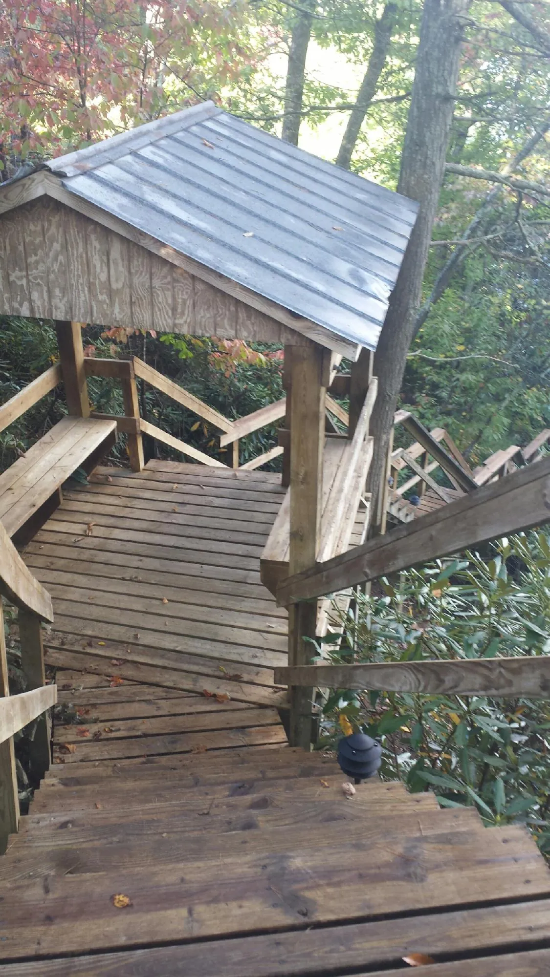 Metal roofed shelter over wooden steps on a wooded walkway — Skylight Repair & Installation work by our crew in Eagle River