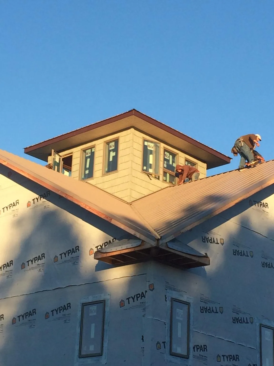 Roofers working around a rooftop cupola on a new metal roof at sunset — Roof Waterproofing in Eagle River by Roofing Brothers